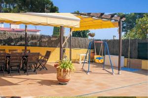 eine Terrasse mit einer Schaukel und einem gelben Regenschirm in der Unterkunft R88 Casa Alegre in Segur de Calafell