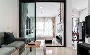 a living room with a couch and a room with a bed at Siamplaengna Residence in Bangkok