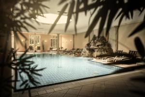 a large swimming pool with lounge chairs in a building at Romantik Hotel Bösehof in Bad Bederkesa