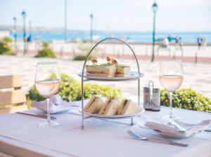 a table with a plate of food and two glasses of wine at Hotel Baia in Cascais