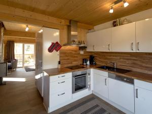 ザンクト・ローレンツェン・オプ・ムーラウにあるModern Chalet in Sankt Georgen ob Murau with outdoor jacuzziの白いキャビネットと木製の壁が備わるキッチン