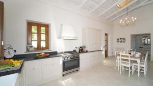Villa La Braja في Licciana Nardi: مطبخ بدولاب بيضاء وطاولة وموقد