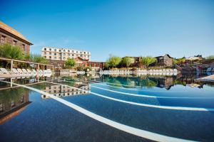 a pool of water with white chairs and buildings at PortAventura Resort - Includes PortAventura Park Tickets in Salou
