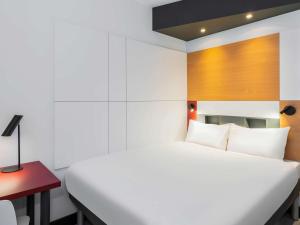 Schlafzimmer mit einem weißen Bett und einem roten Schreibtisch in der Unterkunft ibis budget Oostende Airport in Ostende