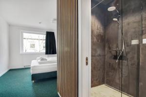 uma casa de banho com um chuveiro e um quarto com uma cama em Sleepcph em Copenhague