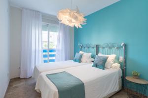 a blue bedroom with two beds and a chandelier at Malagasuite Lux Beach&Pool in Torremolinos