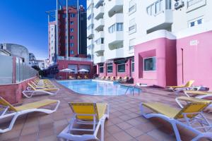 een patio met stoelen en een zwembad in een gebouw bij Hotel Quarteirasol in Quarteira