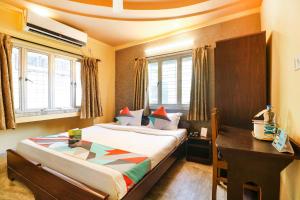 a bedroom with a bed and a desk and windows at FabExpress Harry inn in Kolkata