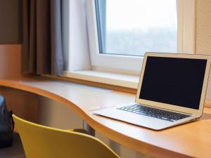 a laptop computer sitting on top of a wooden table at ibis Rotterdam Vlaardingen in Vlaardingen