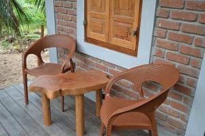 Duas cadeiras e uma mesa de madeira num alpendre em Agro Village Resort , Kalpitiya em Kalpitiya