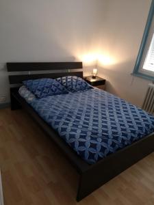 Una cama con un edredón azul en un dormitorio en Hôte "Il était une fois", en Hesdin