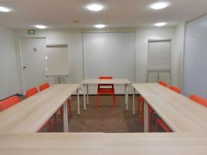 uma sala de conferências com duas mesas e cadeiras vermelhas em ibis Velizy Jouy-En-Josas em Jouy-en-Josas