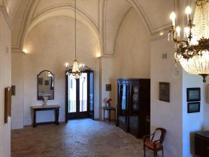 un grand couloir avec un lustre et une chambre avec une table dans l'établissement Palazzo Viceconte, à Matera