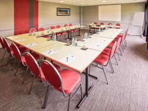 une salle de conférence avec une grande table et des chaises rouges dans l'établissement Ibis Auray, à Auray