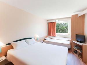 Un dormitorio con una gran cama blanca y una ventana en Ibis Murcia, en Murcia