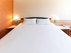 ムルシアにあるイビス ムルシアのランプ2つが備わる客室の大きな白いベッド1台
