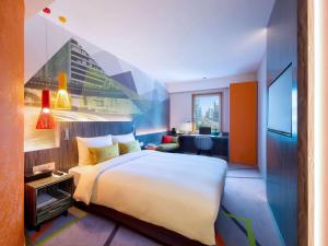 ソウルにあるイビス スタイル アンバサダー ソウル カンナムの大きなベッドとデスクが備わるホテルルームです。