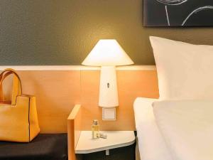 a hotel room with a bed and a table with a lamp at ibis Wien City in Vienna