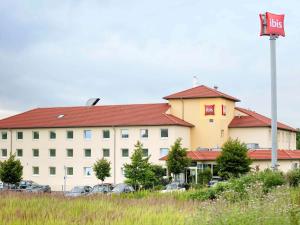 un grand bâtiment avec un panneau d'autobus devant lui dans l'établissement ibis Hotel Köln Airport, à Cologne