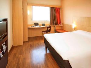 a hotel room with a bed and a desk with a laptop at ibis Vitoria Praia do Canto in Vitória