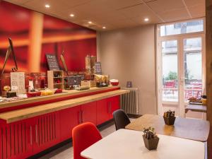 un restaurant avec des armoires rouges et un comptoir avec des tables dans l'établissement ibis Paris Vaugirard Porte de Versailles, à Paris