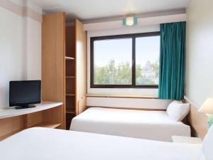 um quarto de hotel com duas camas e uma janela em B&B HOTEL Zaragoza Centro em Saragoça