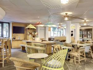 a restaurant with chairs and tables and a kitchen at Novotel Suites Paris Stade de France in Saint-Denis