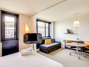 um quarto de hotel com uma cama, um sofá e uma televisão em Novotel Suites Paris Stade de France em Saint-Denis