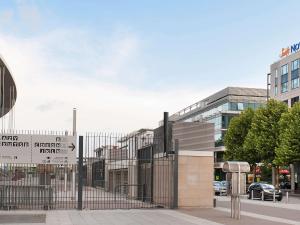 une clôture devant un bâtiment avec un panneau dans l'établissement Novotel Suites Paris Stade de France, à Saint-Denis