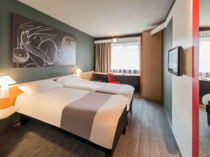 a hotel room with two beds and a tv at ibis München Parkstadt Schwabing in Munich