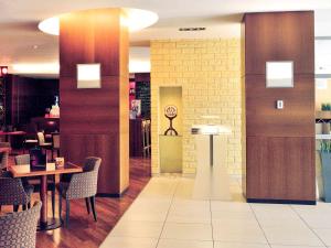 Hotel Mercure Toruń Centrum في تورون: مطعم بطاولات وكراسي وساعة على الحائط