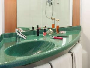 La salle de bains est pourvue d'un lavabo vert et d'un miroir. dans l'établissement Ibis Valencia Bonaire Aeropuerto, à Aldaya