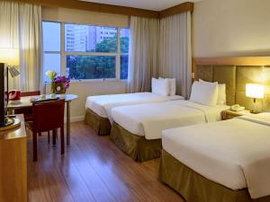 een hotelkamer met 2 bedden en een bureau bij Mercure Sao Paulo Jardins in Sao Paulo