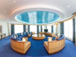 アル・アインにあるメルキュール グランド ジェベル ハフィートのソファと大きなプール付きの広い客室です。