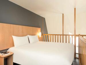 a bedroom with a large white bed and a staircase at ibis Paris Bastille Faubourg St Antoine in Paris +33 photos