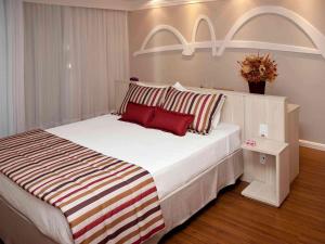 1 dormitorio con 1 cama blanca grande con almohadas rojas en Mercure Brasilia Lider, en Brasilia