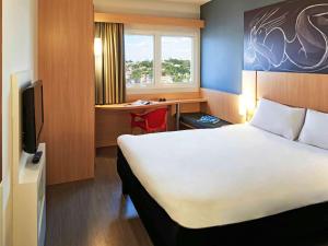 a bedroom with a large bed and a large window at ibis Goiania in Goiânia