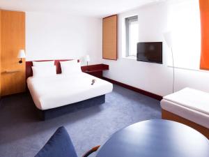 a hotel room with a bed and a tv at Novotel Suites Hannover in Hannover