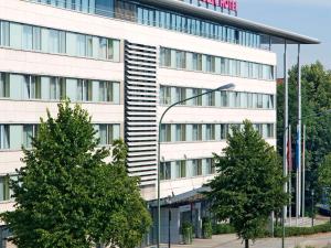 een groot wit gebouw met bomen ervoor bij Mercure Hotel Plaza Essen in Essen