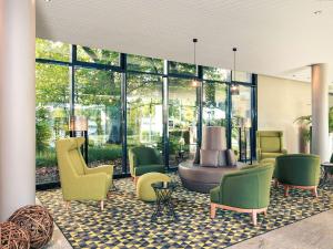 eine Lobby mit Stühlen, einem Tisch und Fenstern in der Unterkunft Mercure Hotel Plaza Essen in Essen