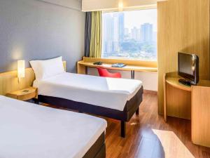 a hotel room with two beds and a desk at ibis Guarulhos Aeroporto in Guarulhos +37 photos
