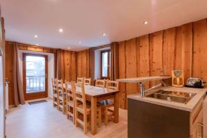 cocina con paredes de madera, mesa y fregadero en Clot Saint Joseph - Gites & Chambres d'Hôtes en Vallouise