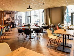 um restaurante com mesas, cadeiras e janelas em Hotel ibis Dijon Centre Clemenceau em Dijon