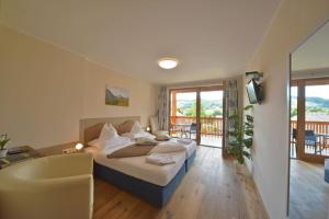 a bedroom with a bed and a tub and a balcony at Gästehaus Bärwald in Seeboden