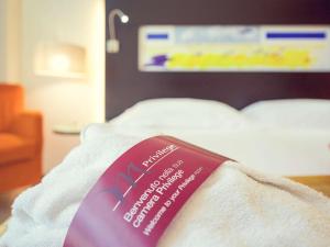 a pink sign sitting on top of a bed at Hotel Mercure Siracusa in Syracuse