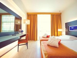 a hotel room with two beds and a desk at Hotel Mercure Siracusa in Syracuse