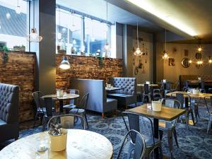 uma sala de jantar com mesas, cadeiras e janelas em Novotel Liverpool Centre em Liverpool