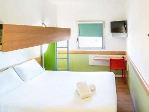 a bedroom with a white bed and a desk and a window at ibis budget Leicester in Leicester