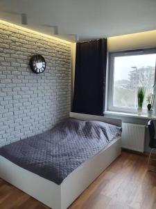 a bedroom with a bed against a brick wall with a clock at Iława Apartamenty in Iława