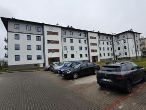 a row of cars parked in a parking lot in front of a building at Iława Apartamenty in Iława